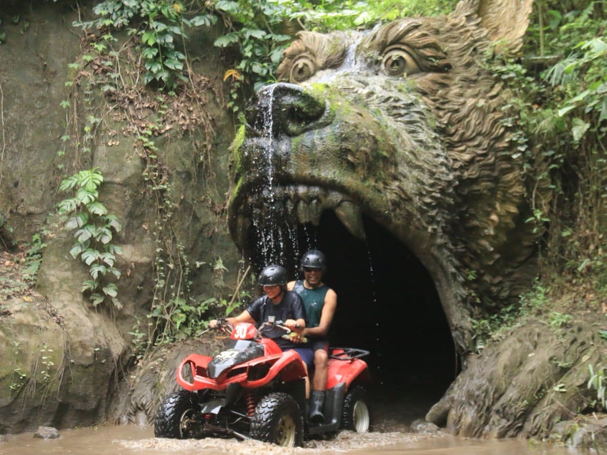 Rider on an ATV quad bike splashing through a muddy jungle trail