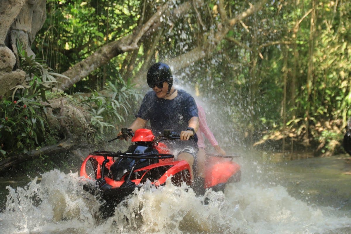 Rider blasting an ATV through a jungle waterfall in Ubud