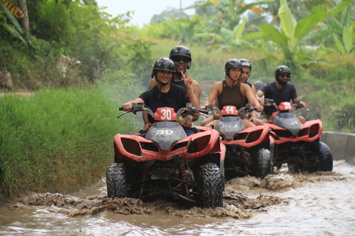 Convoy of ATVs churning through a muddy river