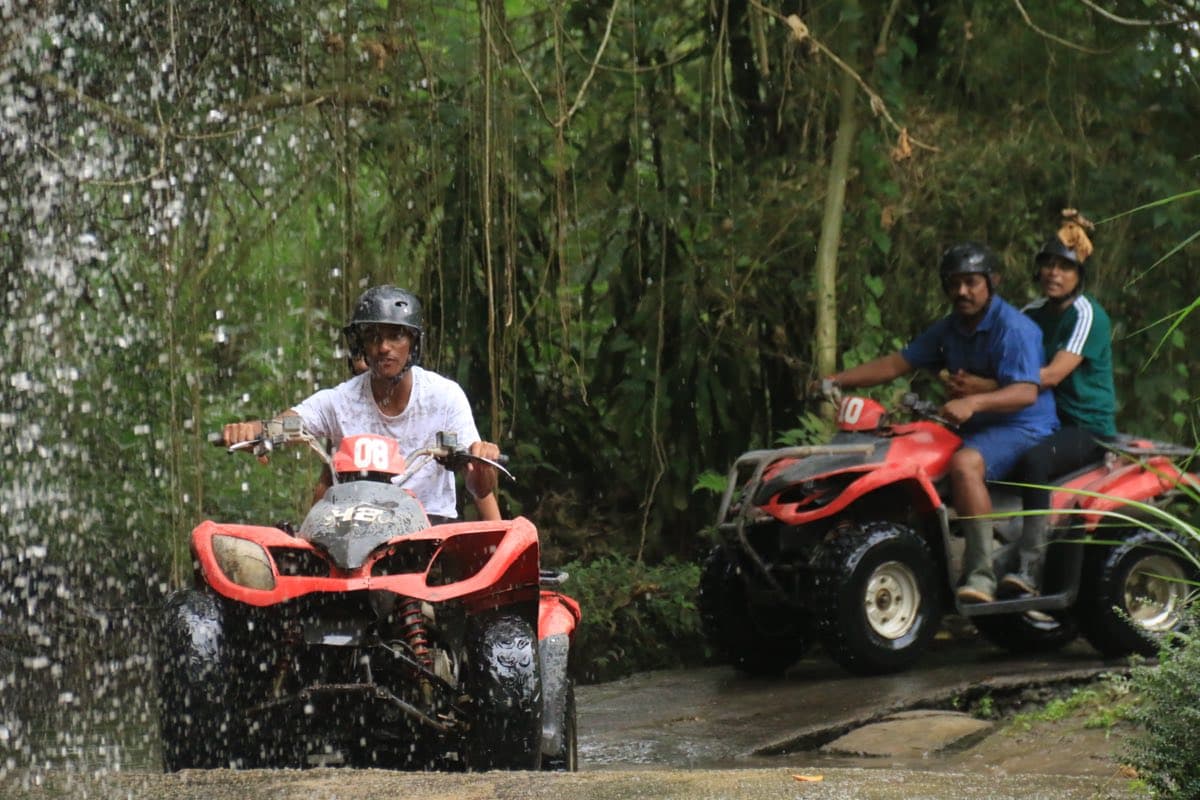 ATV riding through a waterfall with another quad behind