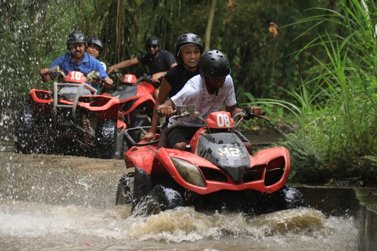 Convoy of red ATVs crossing a jungle river
