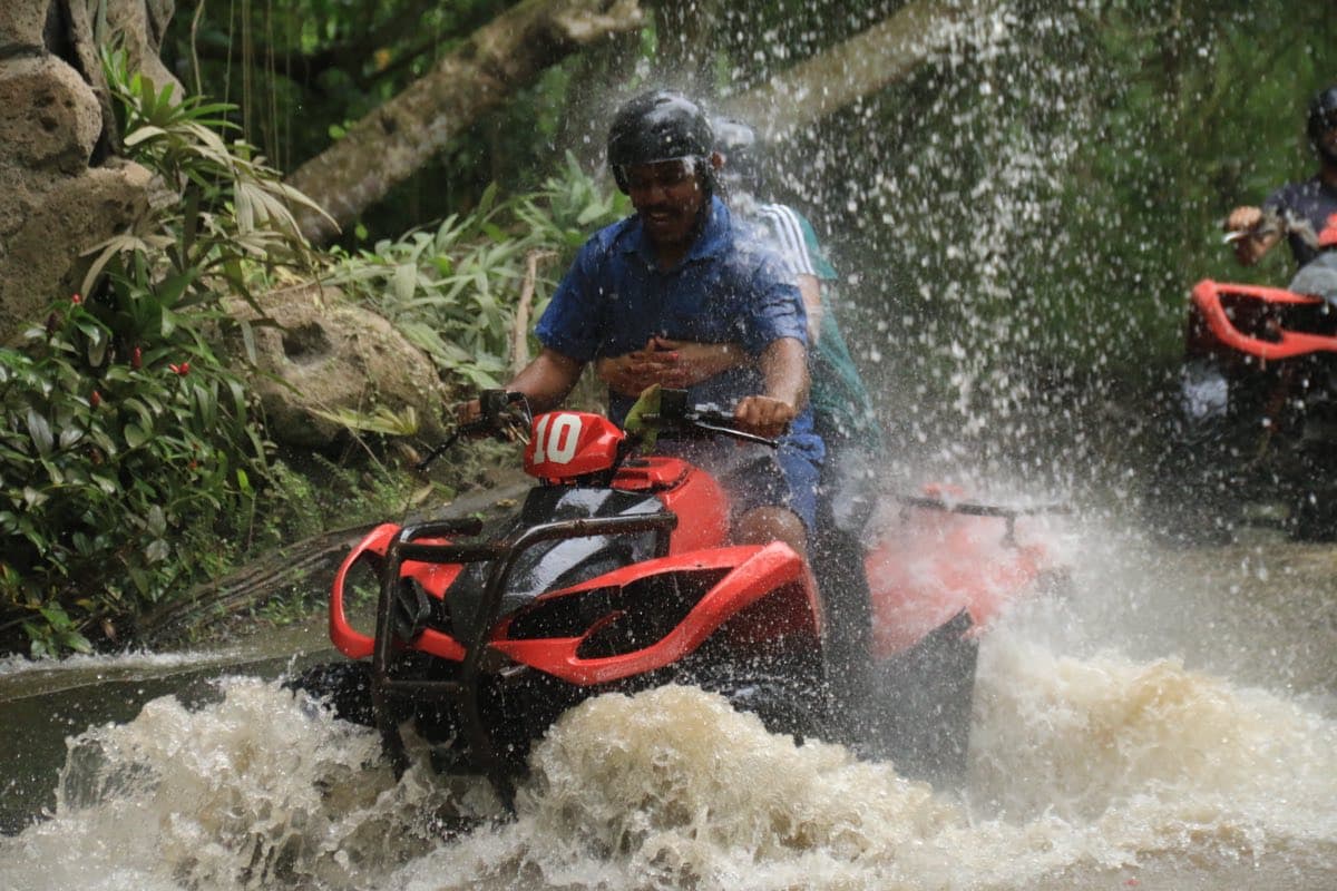 ATV blasting through a powerful jungle waterfall