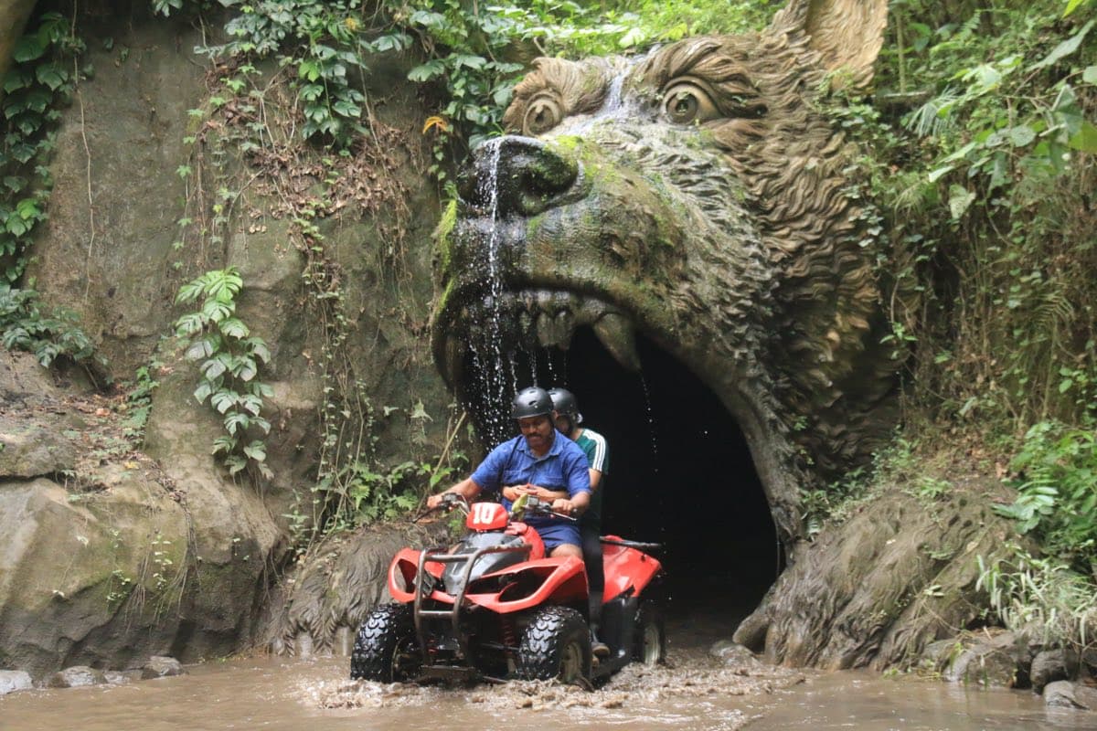 ATV speeding past the Ride Bali Adventure sign through mud
