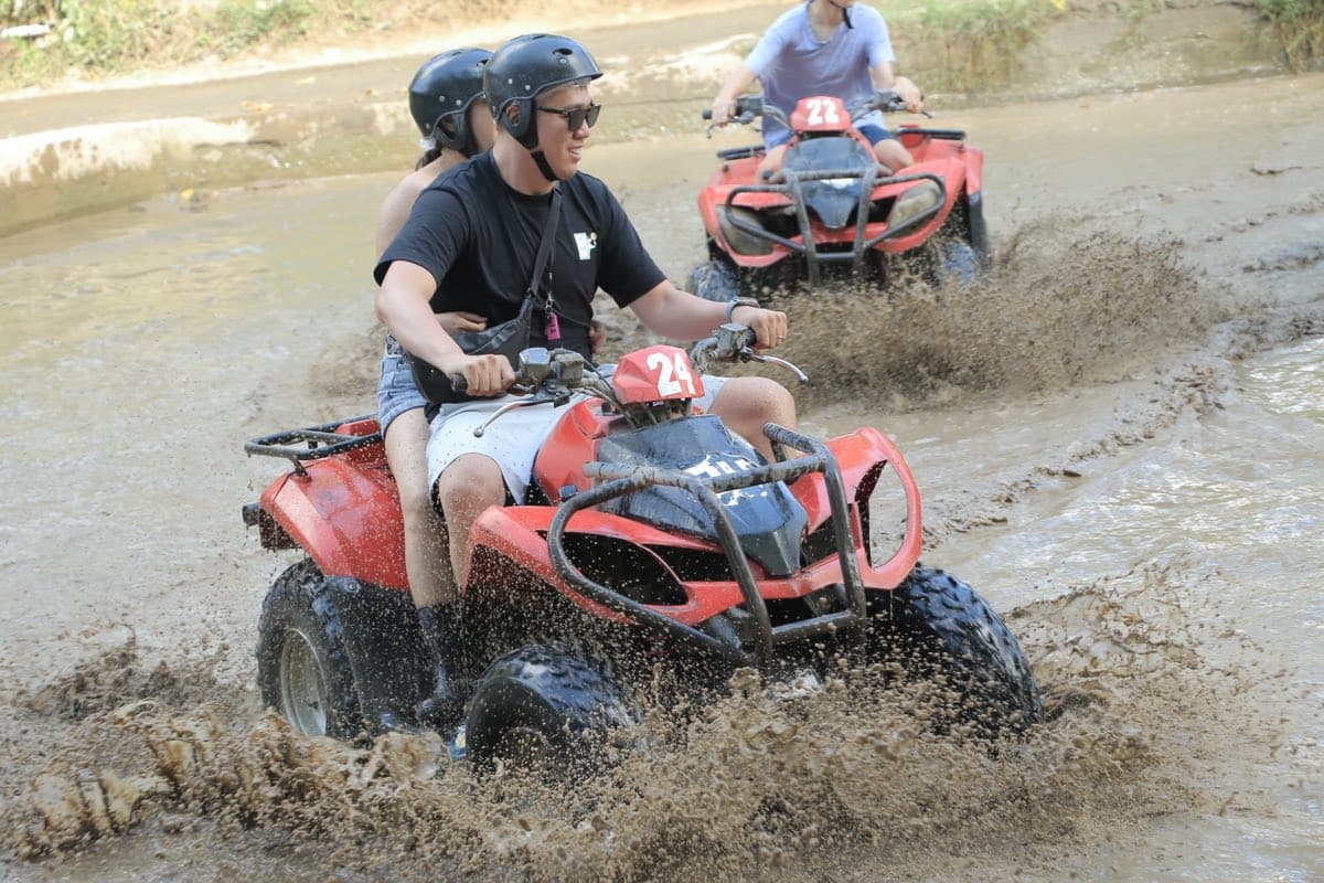 Rider charging an ATV through a dark jungle waterfall