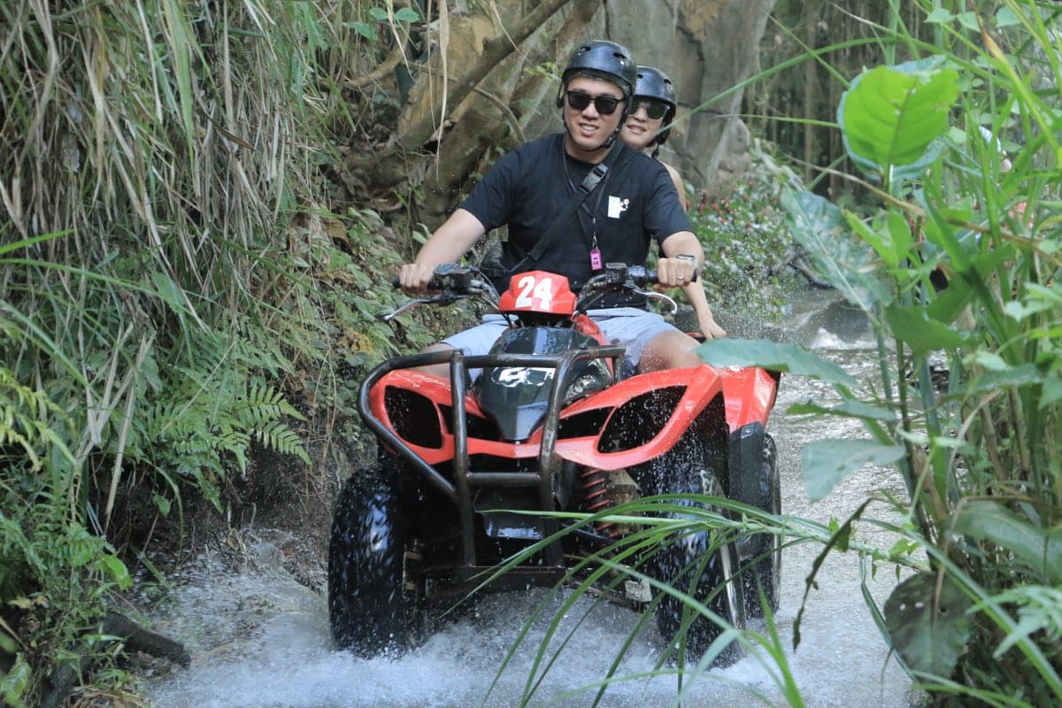 ATV riding a narrow water channel through dense jungle