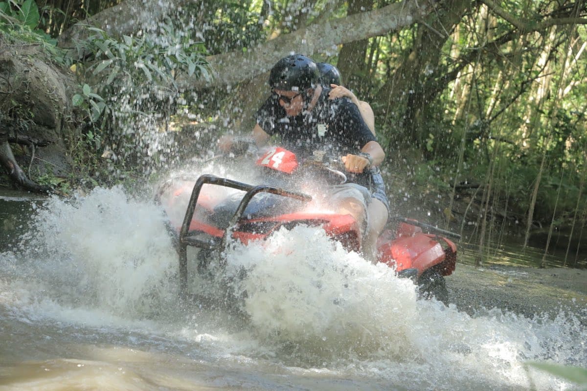ATV charging through a spray of river water on the trail