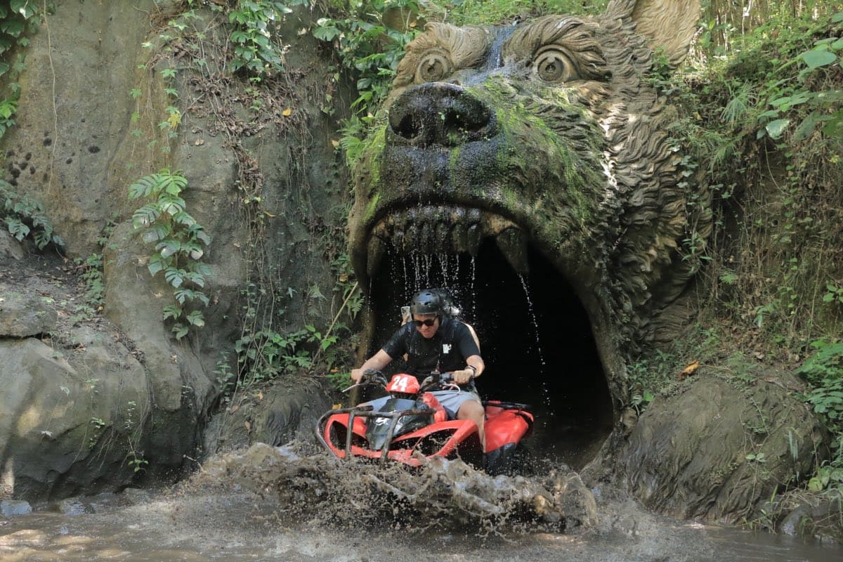 ATV emerging from the carved beast-head cave waterfall tunnel