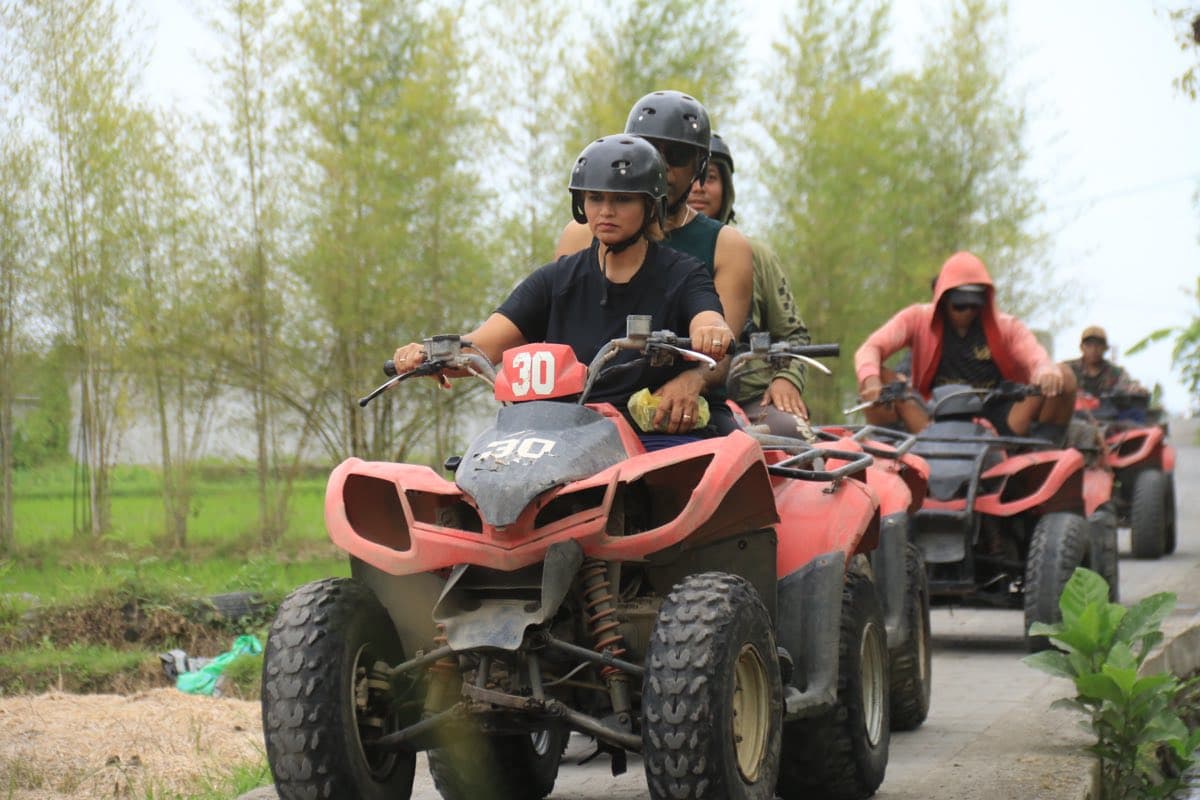 Riders lined up on ATVs along a country track