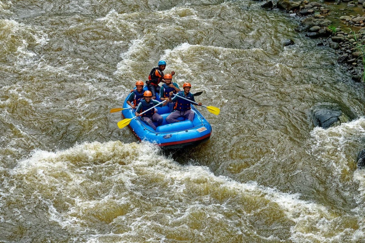 Rafting team paddling through frothing white-water rapids