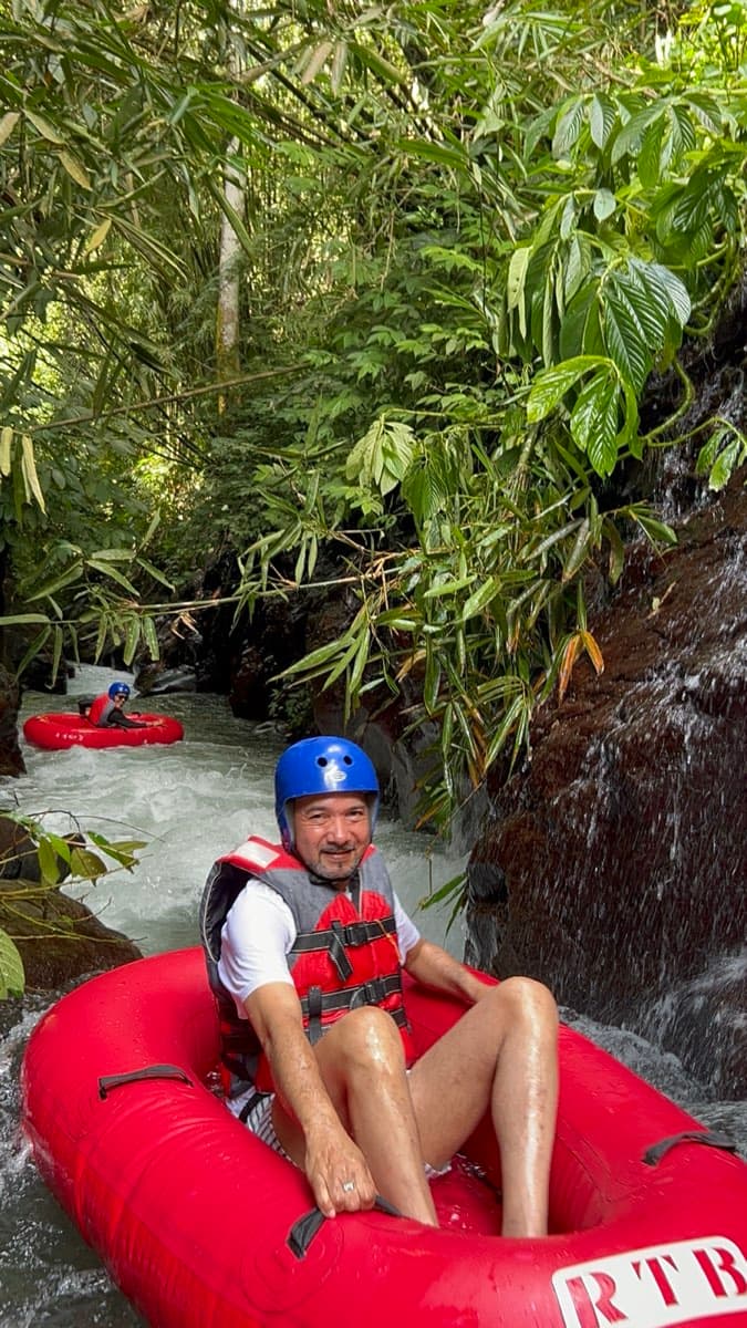 Ein Fahrer entspannt im Reifen in einer üppig grünen Schlucht an einem kleinen Wasserfall