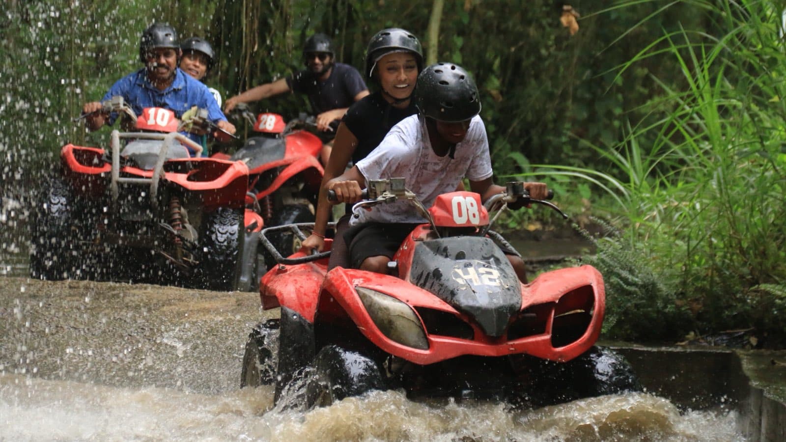 Two riders on an ATV at the carved beast-head cave waterfall on the Ubud jungle trail